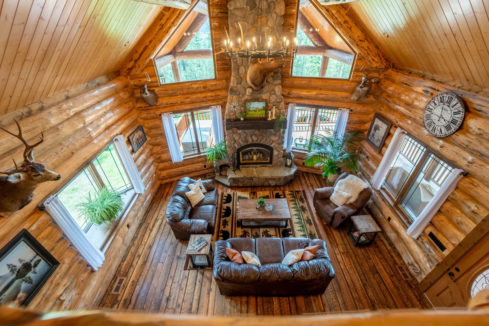 Log home living room with stone fireplace and chandelier