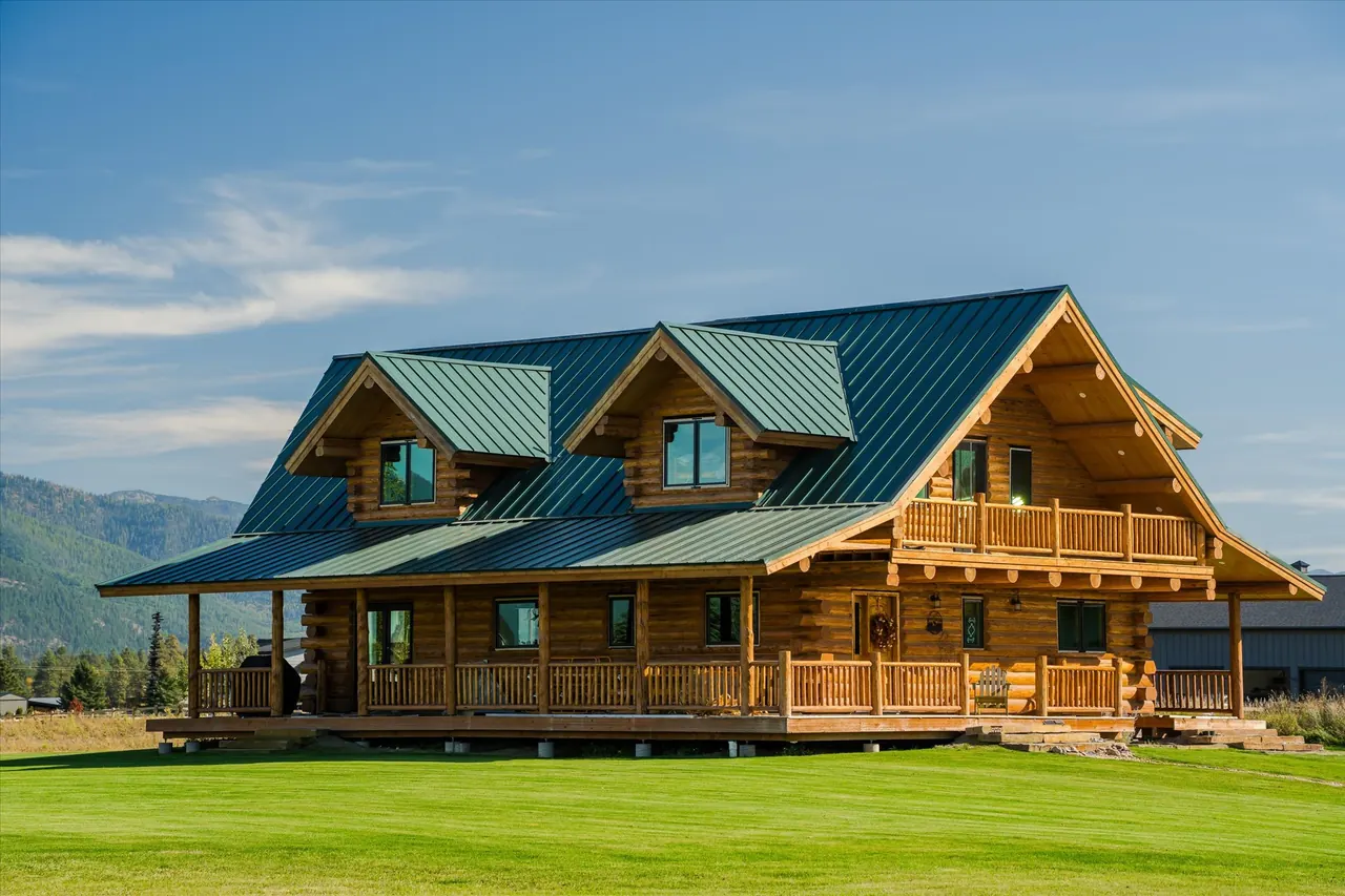 Glacierview exterior with green roof and wraparound porch, Meadowlark Log Homes