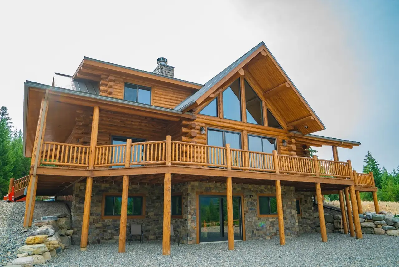 Granite Peak rear exterior with deck and stone base, Meadowlark Log Homes