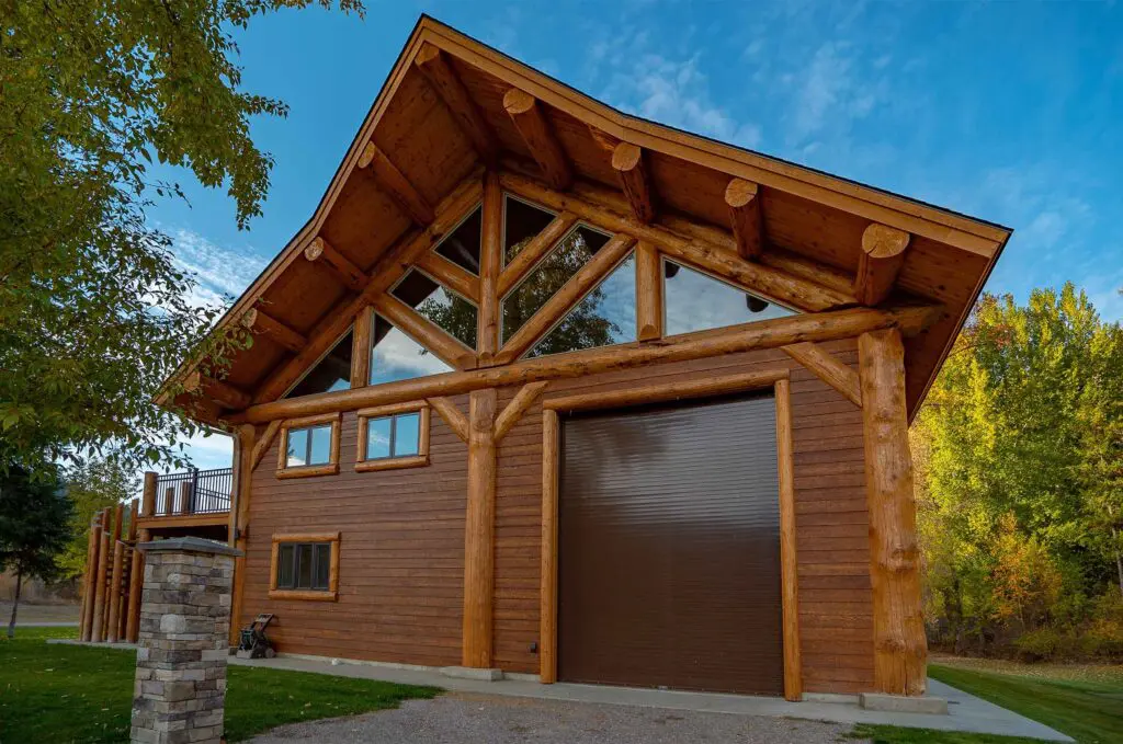 Wooden cabin with large windows and garage door in forest setting