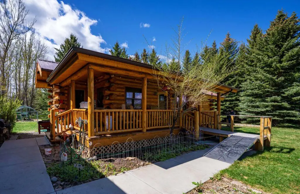Cozy wooden cabin surrounded by green trees and blue sky
