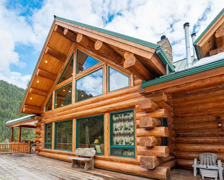 Rustic log home exterior with large windows under blue sky