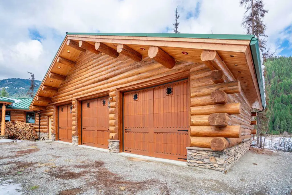 Wooden log cabin garage with scenic forest backdrop