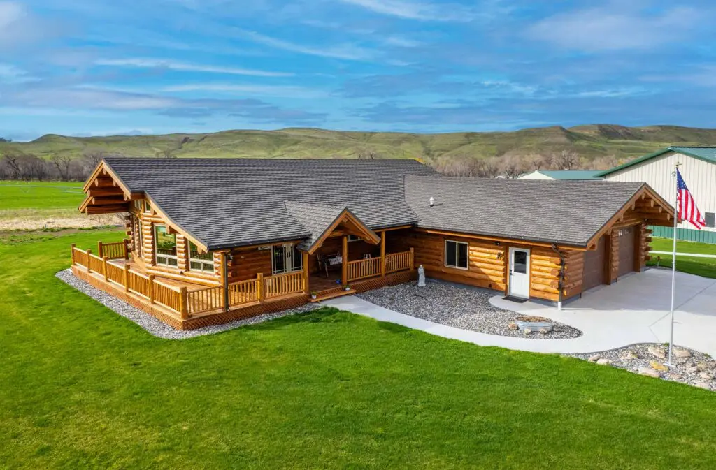 Rustic log cabin with green lawn and scenic mountain background