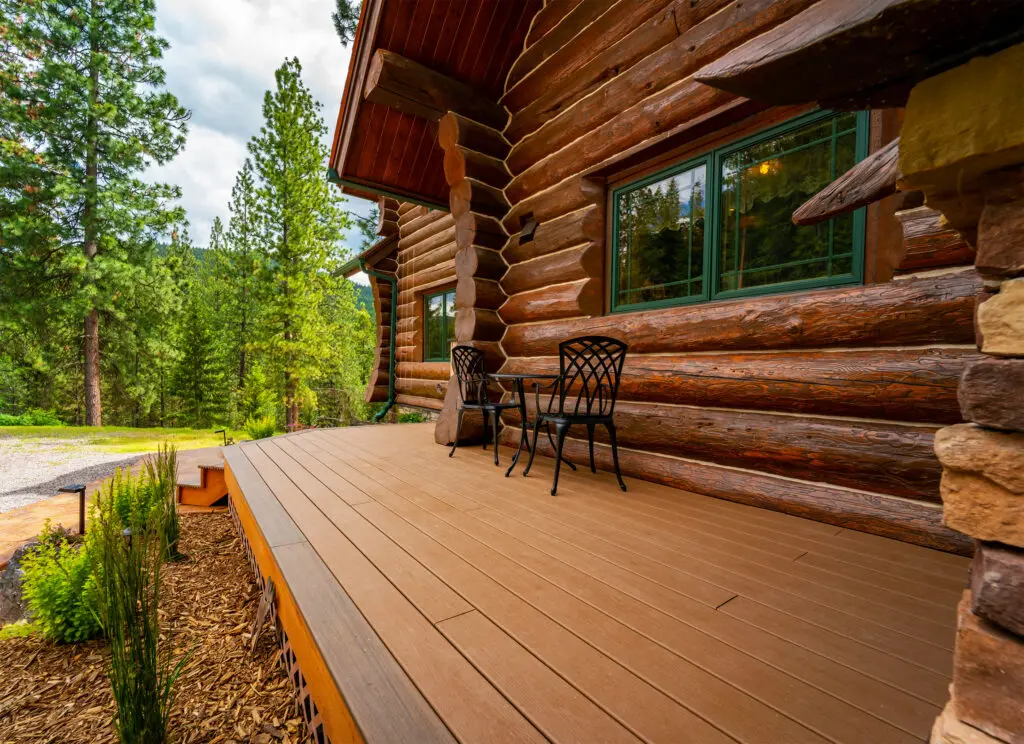 Rustic log home porch with chairs in a forest setting