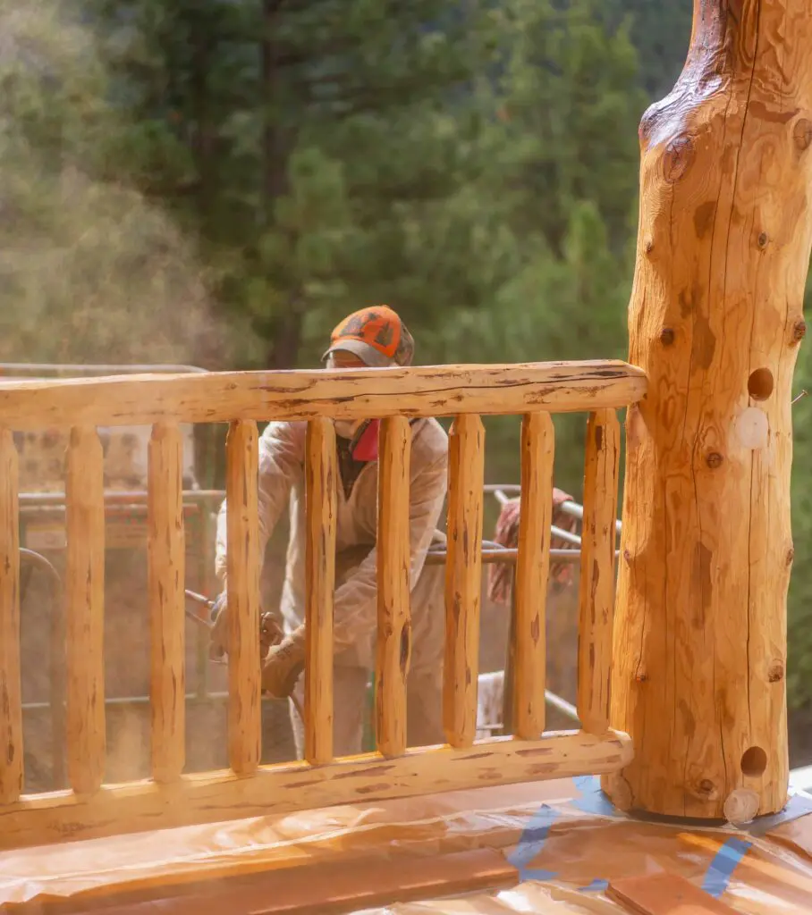 Worker sanding a wooden balcony in a forest environment