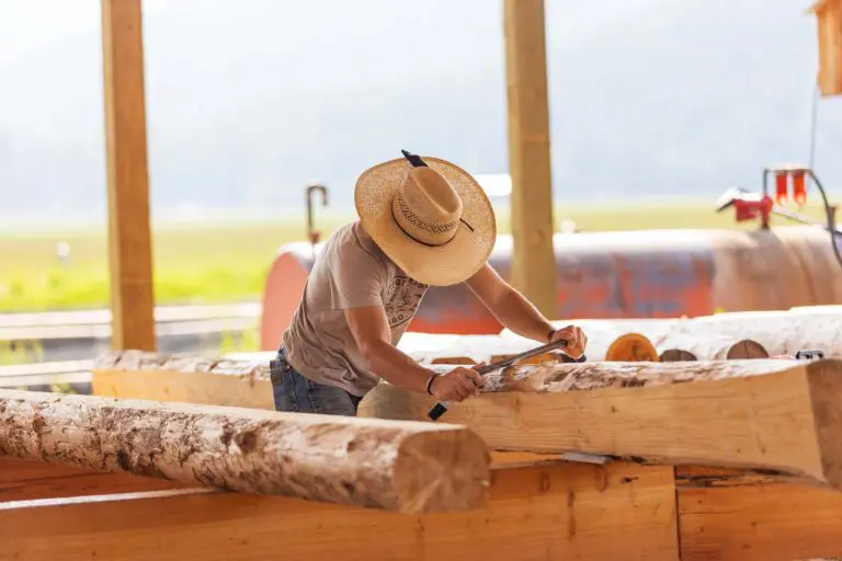 a man in a straw hat cutting a log