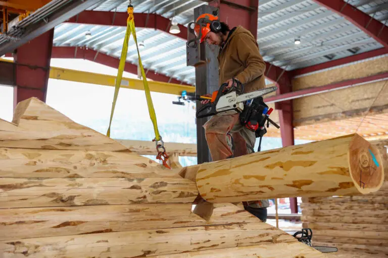 Log builder using chainsaw for precise woodwork construction